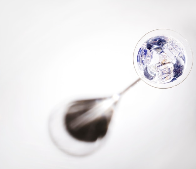 Glaçons dans le verre à martini avec une ombre noire isolée sur fond blanc