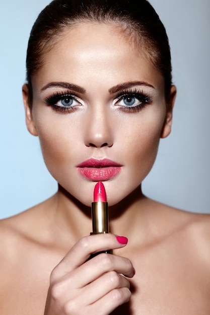 Glamour closeup portrait of beautiful sexy Caucasian brunette young woman model appliquer le maquillage rouge à lèvres sur ses lèvres avec une peau parfaitement propre