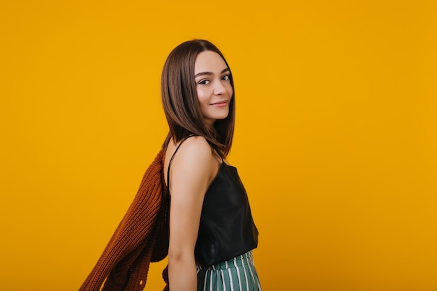 Glamour jeune femme avec une coiffure droite posant. fille brune détendue isolée.