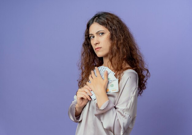 Gourmand jeune jolie fille tenant de l'argent isolé sur un mur bleu