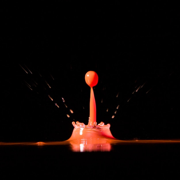 Goutte lumineuse tombant dans l&#39;eau sur fond noir