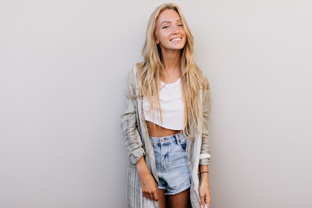 Gracieuse dame heureuse aux cheveux longs, souriant à la caméra. Photo intérieure d'une charmante femme européenne exprimant des émotions positives.