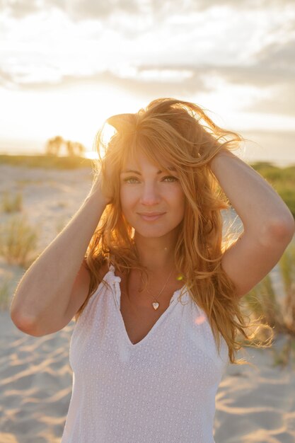 Gracieuse femme au gingembre enjoing incroyable coucher de soleil sur la plage.