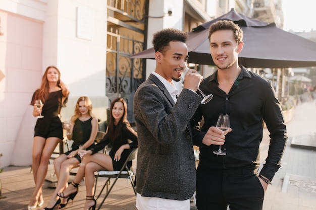 Photo gratuite gracieuses dames brune est assise sur une chaise avec les jambes croisées et regardant les gars posant au premier plan