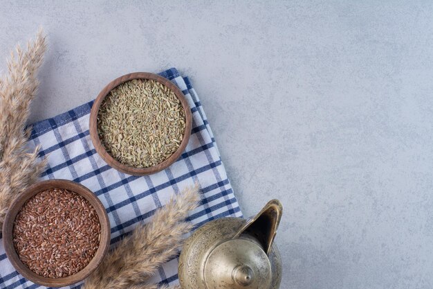 Graines d'anis sèches brunes et vertes dans des gobelets en bois.