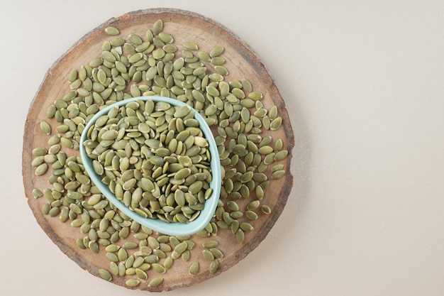 Graines de citrouille vertes dans une tasse en céramique sur béton.