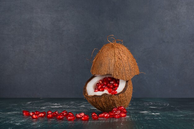 Graines de grenade à l'intérieur de la noix de coco sur la surface en marbre