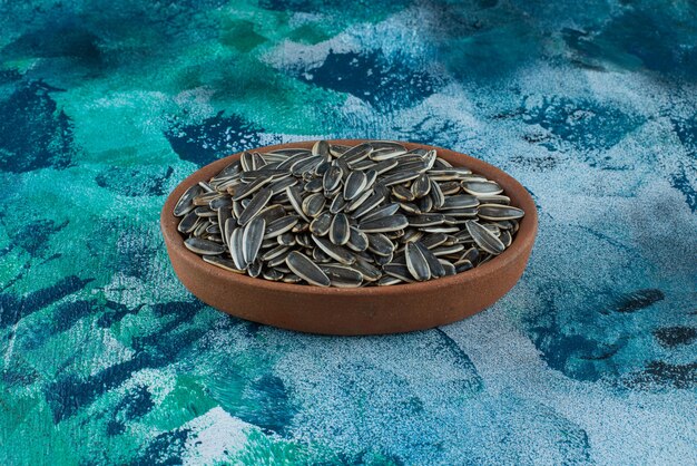 Photo gratuite graines de tournesol non pelées dans un bol en argile, sur la table en marbre.