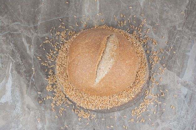 Grains d'avoine non cuits avec miche de pain sur une surface en marbre