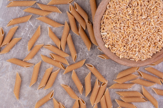 Photo gratuite grains de blé dans une tasse en bois avec des pâtes autour