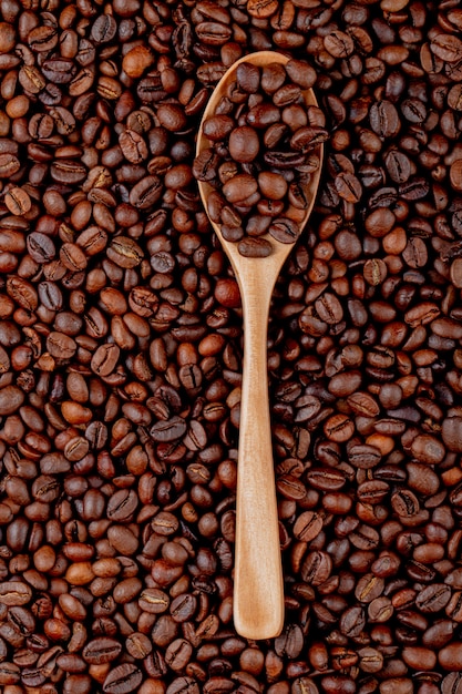 Grains de café dans une cuillère en bois sur la vue de dessus des grains de café