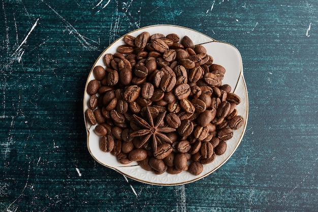 Grains de café dans une soucoupe en céramique blanche.