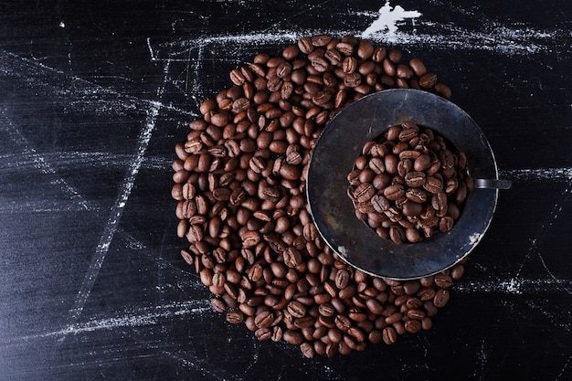 Grains de café dans la soucoupe noire.