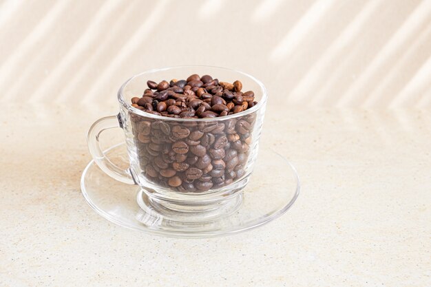 Grains de café dans une tasse en verre sur une table.