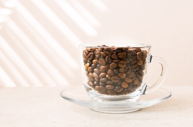 Grains de café dans une tasse en verre sur une table.