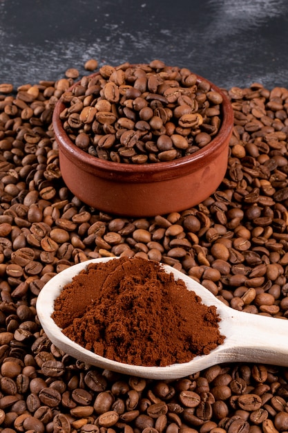 grains de café avec du café moulu dans une cuillère en bois