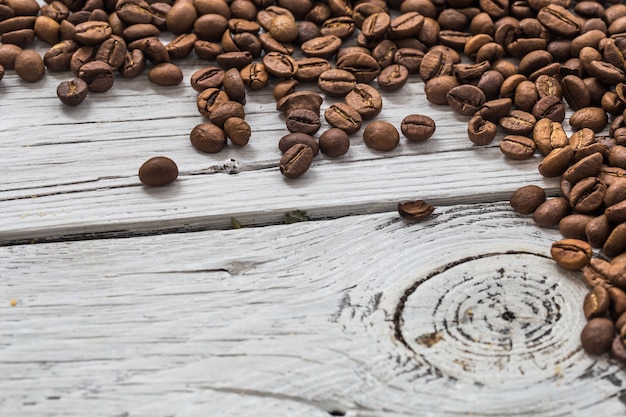 Grains de café sur un mur en bois blanc, gros plan