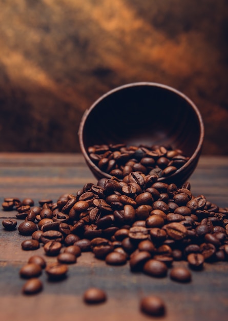 Photo gratuite grains de café noirs dans un bol sur une table brune