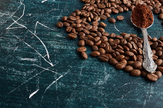 Grains de café et poudre dans une cuillère métallique.