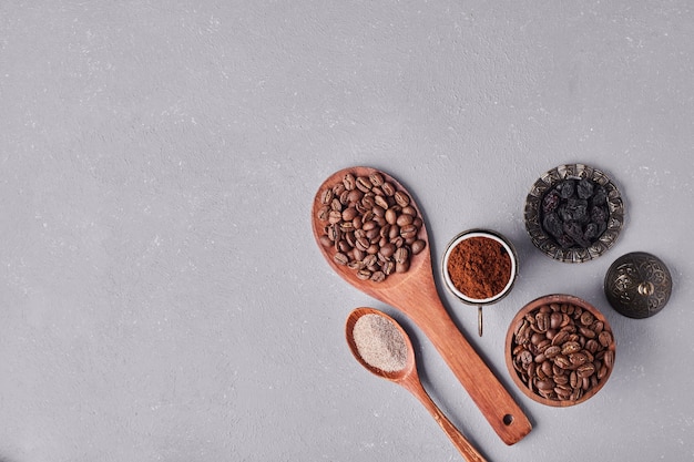 Grains de café et poudres dans des cuillères en bois.