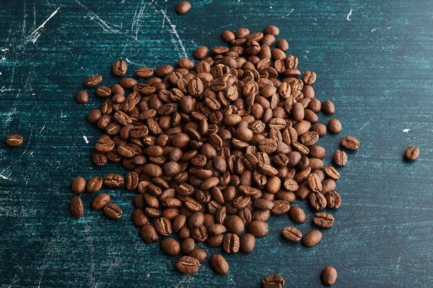 Grains de café sur une surface bleue.