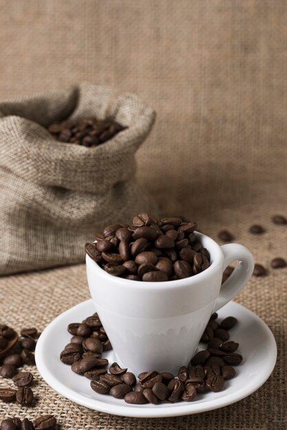 Grains de café torréfiés dans une tasse blanche