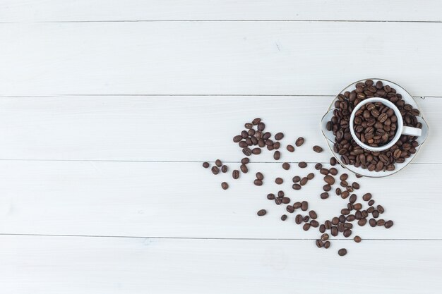 Les grains de café en vue de dessus de tasse et soucoupe sur un fond en bois