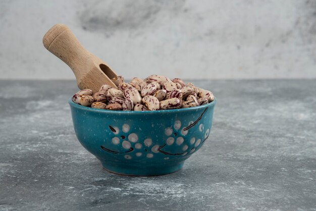 Grains de haricots crus dans un bol bleu.