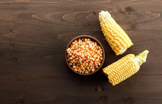 Grains de maïs dans une assiette d'argile avec des tranches vue de dessus sur une table en bois