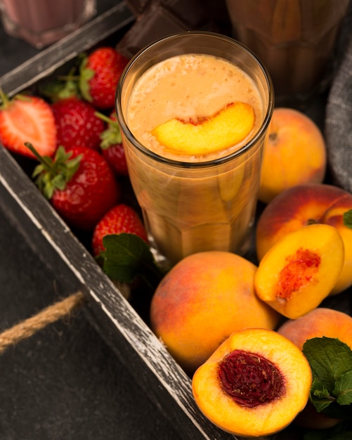 Photo gratuite grand angle de verre de milkshake avec pêche et fraises