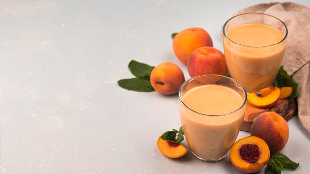 Grand angle de verres de milkshake avec des pêches et de l'espace de copie