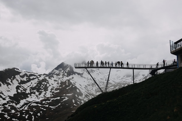 Grand angle de vue bas des gens sur un quai près des montagnes couvertes de neige