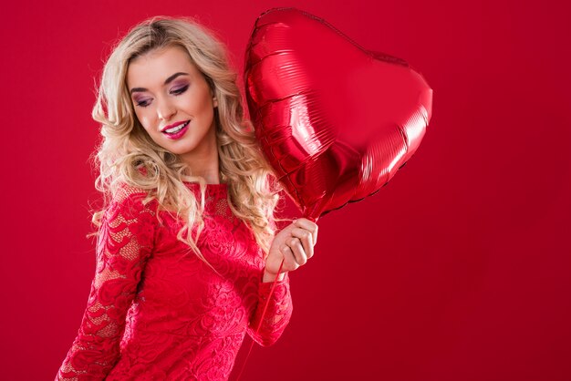 Grand ballon rouge en forme de cœur tenu par une femme joyeuse