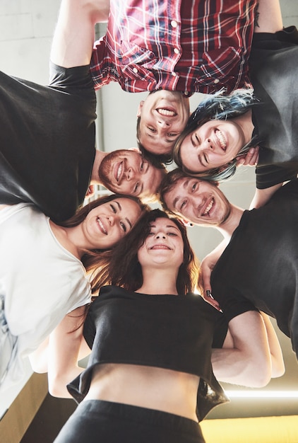 Un grand groupe d'amis souriants étreignant ensemble.