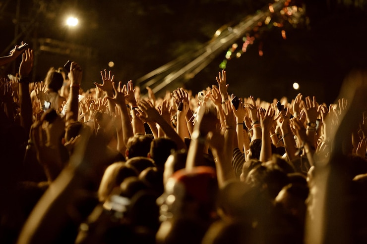 Photo gratuit un grand groupe de fans avec les bras levés s'amusent lors d'un concert de musique la nuit.