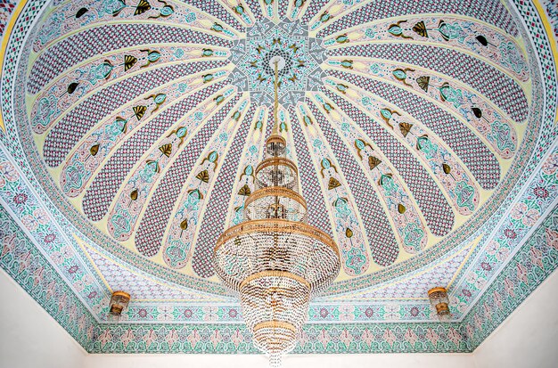 Photo gratuite grand lustre doré sur un plafond panaché avec ornement religieux traditionnel islamique.