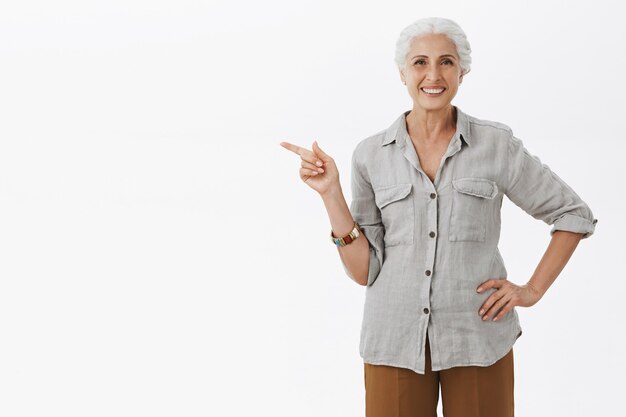 Grand-mère assez souriante pointant le doigt à gauche et montrant la publicité