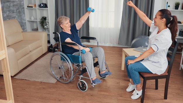 Grand-mère invalide en fauteuil roulant faisant une thérapie de récupération avec un médecin. Infirmière handicapée handicapée en convalescence aide professionnelle infirmière, traitement et réadaptation en maison de retraite médicalisée