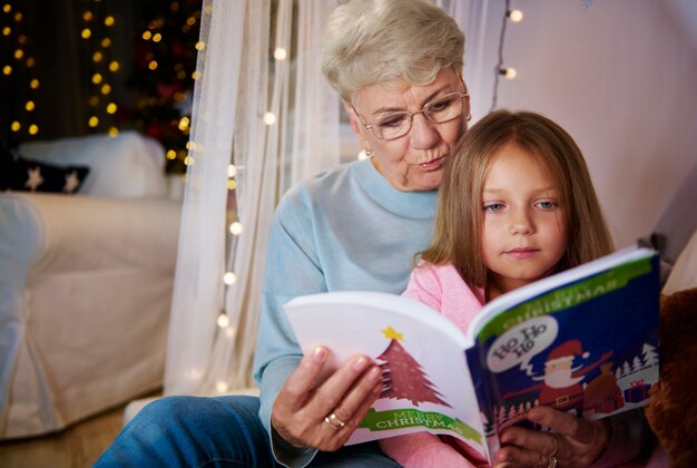 Grand-mère et petite-fille lisant un livre de contes au lit