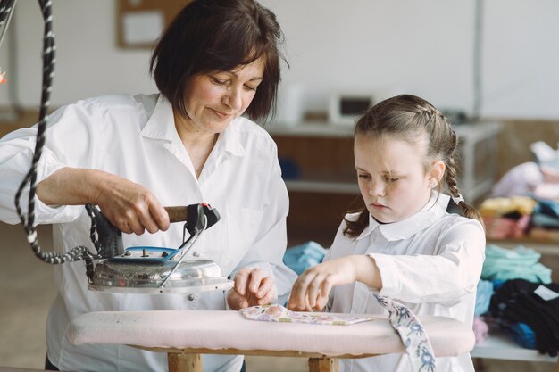 Grand-mère avec petite-fille de vêtements en fer dans l'usine