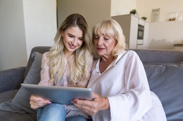 Grand-mère souriante et sa petite-fille en regardant une tablette