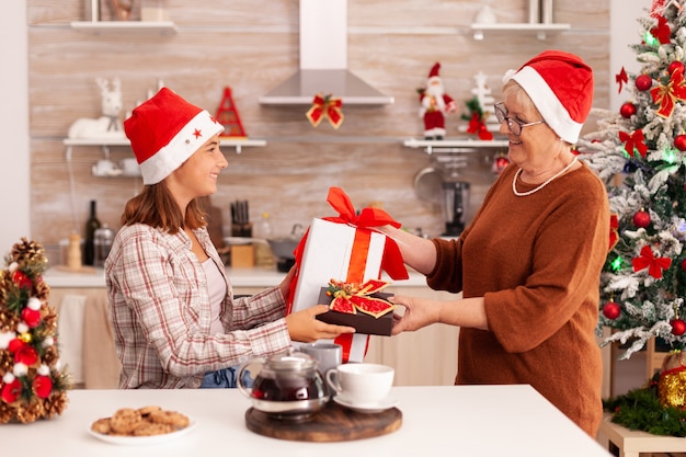 Grand-mère surprenante petite-fille avec cadeau d'emballage de Noël