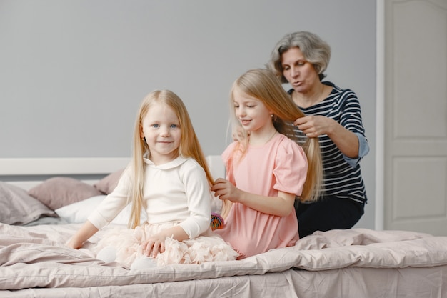 Photo gratuite grand-mère tressant les cheveux de sa petite-fille. deuxième soeur de tressage de petite-fille. maison confortable, relations familiales.