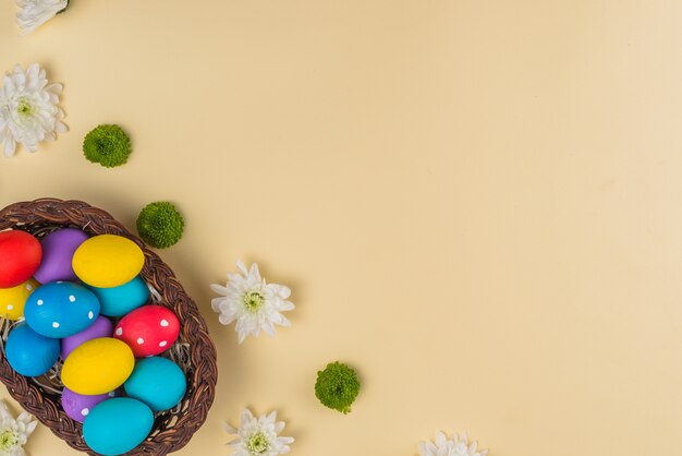 Grand panier avec des oeufs de Pâques colorés sur la table