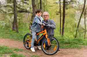 Photo gratuite grand-père apprenant à son petit-fils à faire du vélo