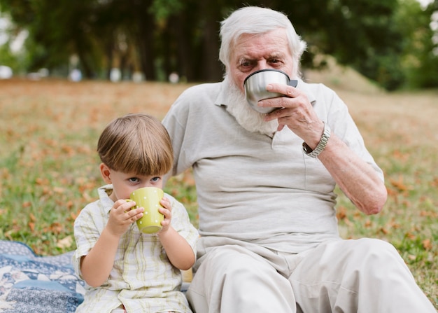 Grand-père et petit-fils au pique-nique buvant du thé