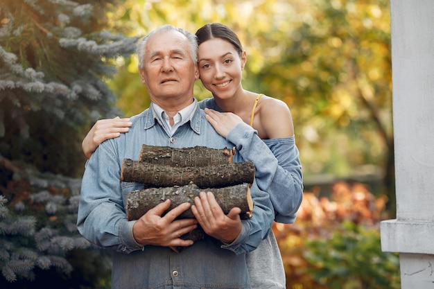 Grand-père Avec Petite-fille Dans Une Cour Avec Du Bois De Chauffage Dans Les Mains