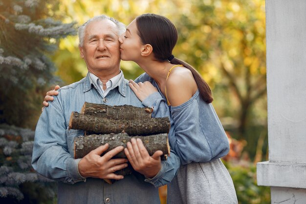 Grand-père avec petite-fille dans une cour avec du bois de chauffage dans les mains