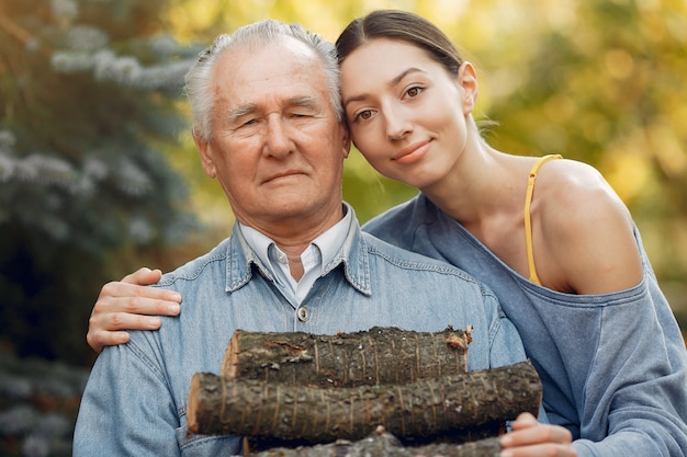 Photo gratuite grand-père avec petite-fille dans une cour avec du bois de chauffage dans les mains