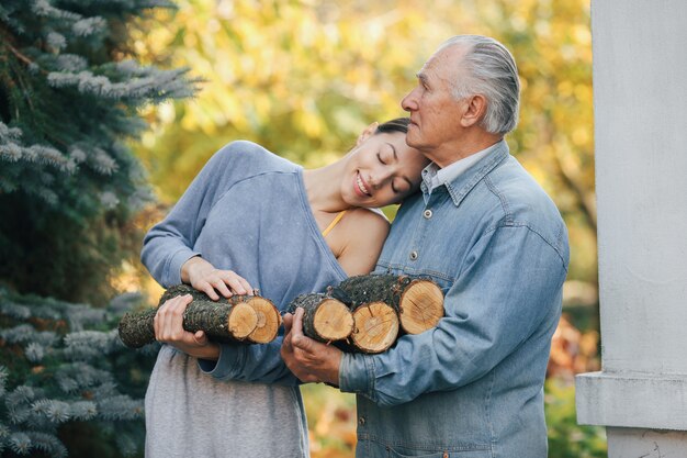 Grand-père avec petite-fille dans une cour avec du bois de chauffage dans les mains